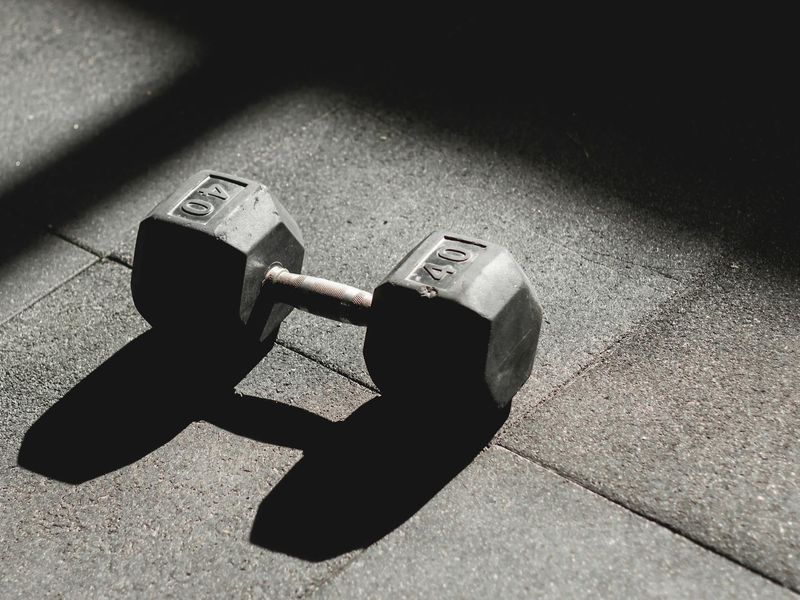 Dumbbells and gym equipment on a dark floor in a minimalist gym